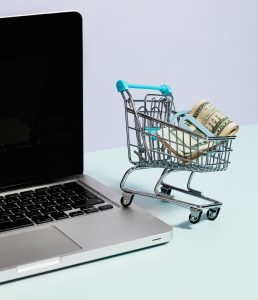 shopping-cart-with-money-on-top-of-a-laptop
